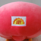 A close-up of a red plush toy with small yellow feet and a sewn-on label that reads 'VEGI PET' on a white background.