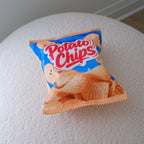 A miniature bag of potato chips resting on a textured white surface against a neutral gray background.