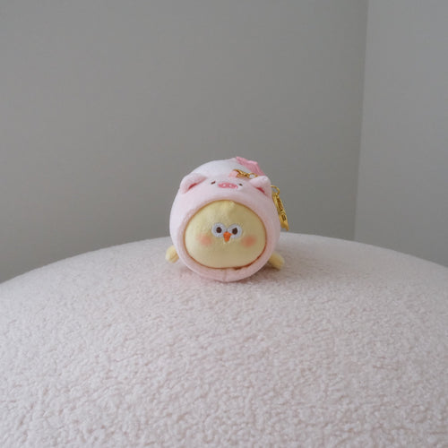 Yellow chicken plush in a pink pig costume with a gold keychain attachment