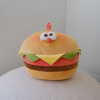 A plush toy shaped like a chicken burger with a cute face, sitting on a textured white surface against a plain light gray background.