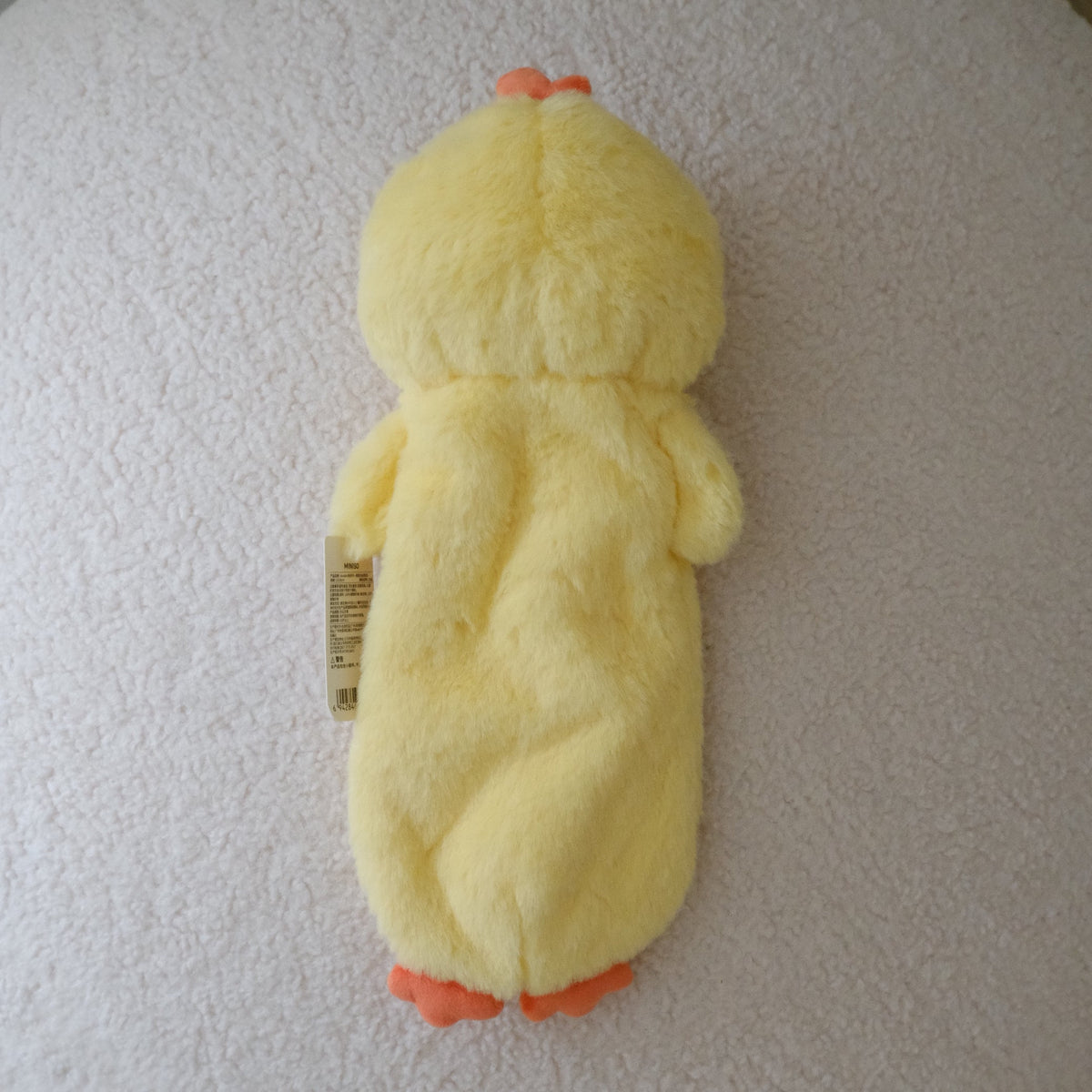 A yellow plush chicken with orange beaks and feet, lying on its back on a round, textured off-white ottoman.