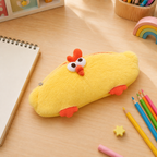 A yellow plush chicken-shaped pencil case with orange feet and an orange crown, placed on a light wood desk surrounded by school supplies including colored pencils, a notebook, and a star eraser.